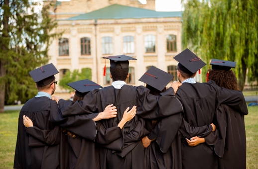 Group of graduating students in caps and gowns hugging each other
