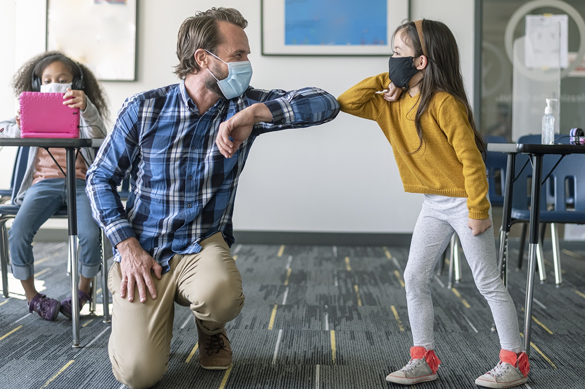 teacher and student bump elbows during pandemic