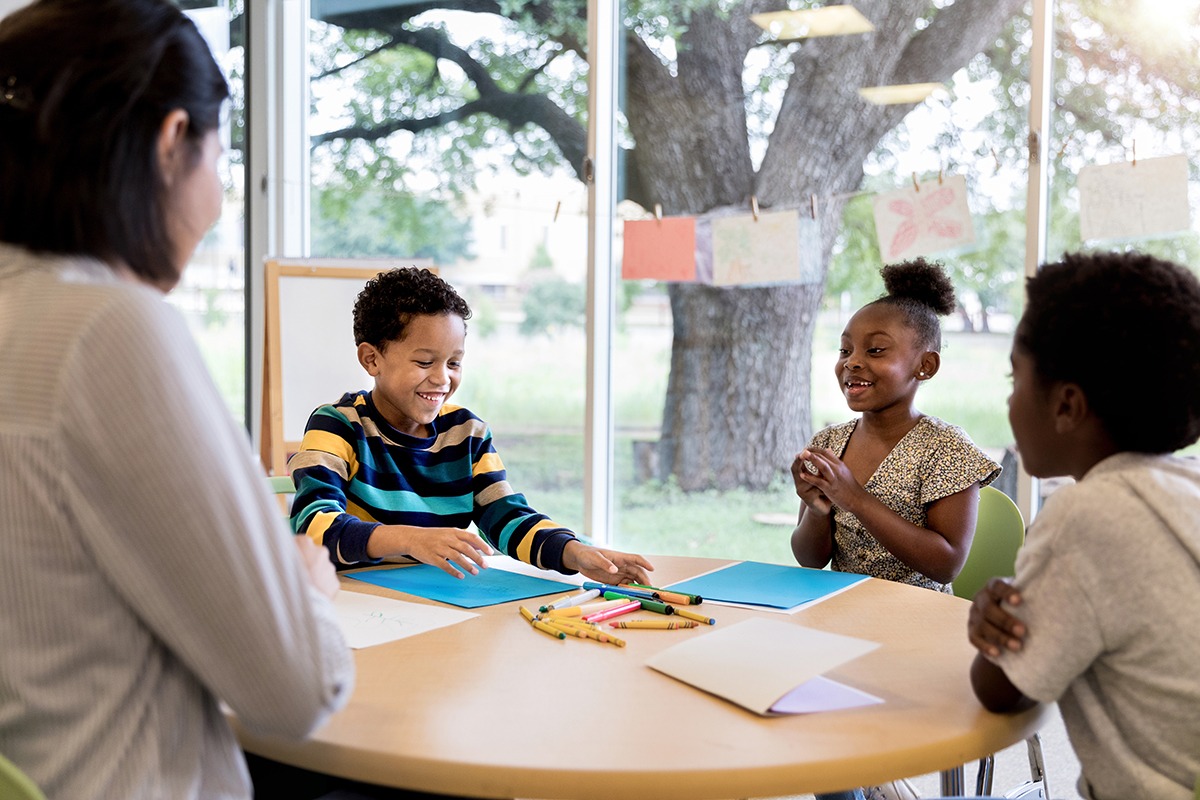 3 students and a teacher engaged in a lesson in a classroom