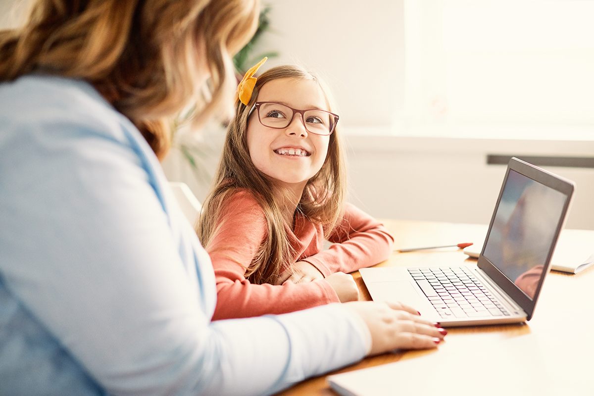 student looks up to teacher while working on a laptop