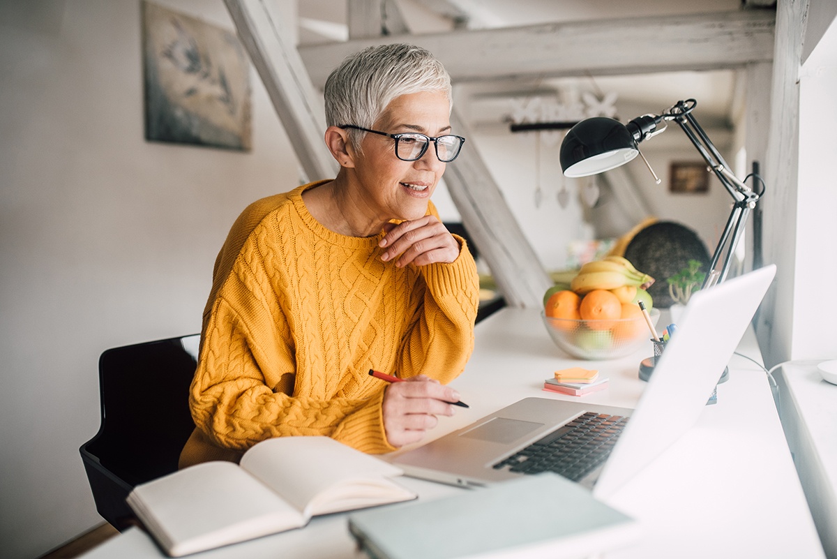 Educator sits in front of a laptop with a pen in hand