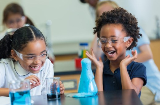 Two elementary students watching beaker spill over