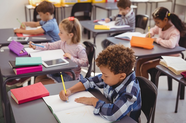 Elementary students writing in notebooks at desks