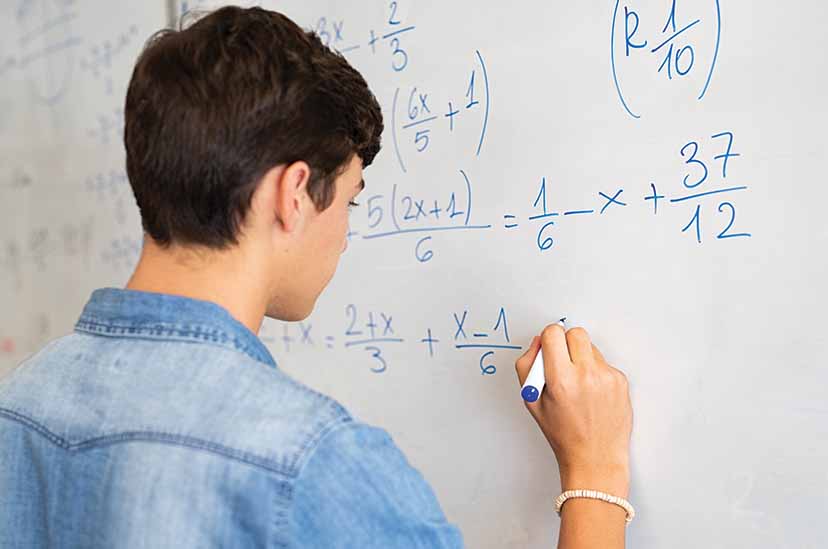 Student solves math problem on whiteboard
