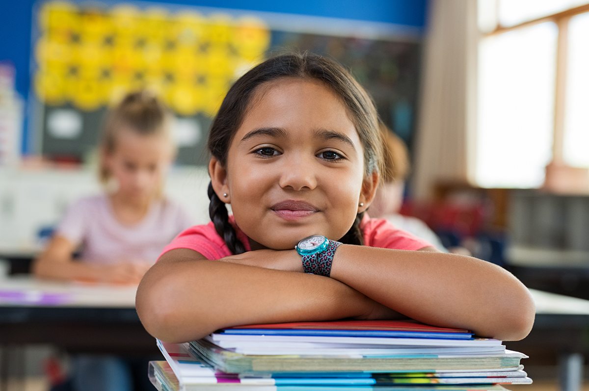 Student in classroom resting on a stack of books