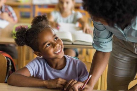 Elementary student smiling up at teacher