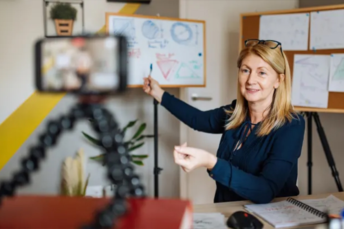 Instructor pointing at a white board while presenting to a camera