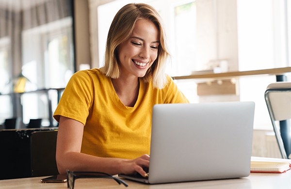 Smiling educator typing on laptop