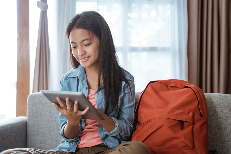 student working on assignments at home using tablet