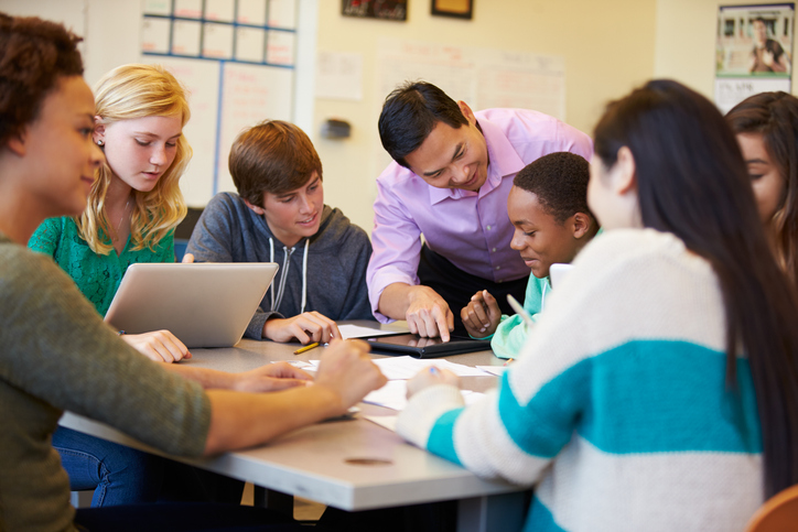 High School Students With Teacher In Class Using Laptops Smiling