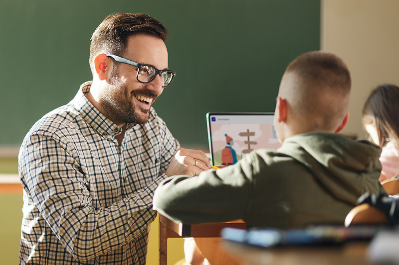 Smiling educator typing on laptop