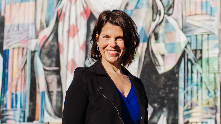 Kathy Swan standing in front of a building with a mural of Abraham Lincoln.