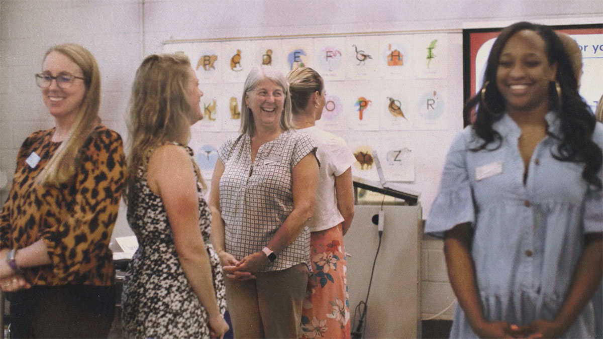 A group of teachers stands back to back in a classroom during an activity at the School District of Philadelphia’s Summer Institute.