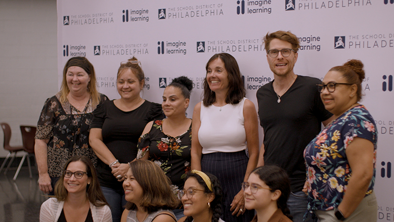 A group of educators pose for a photo in front of a backdrop.