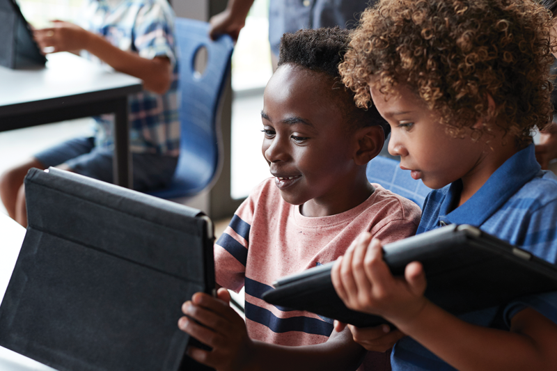 Smiling educator looking at laptop whille wearing headphones