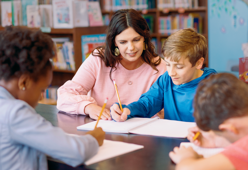 Teacher assisting high school student in class