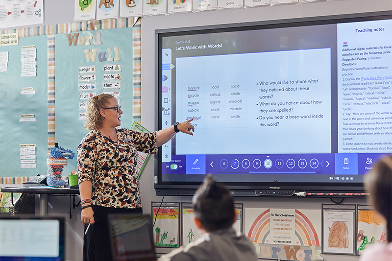 teacher giving instruction at the front of a classroom