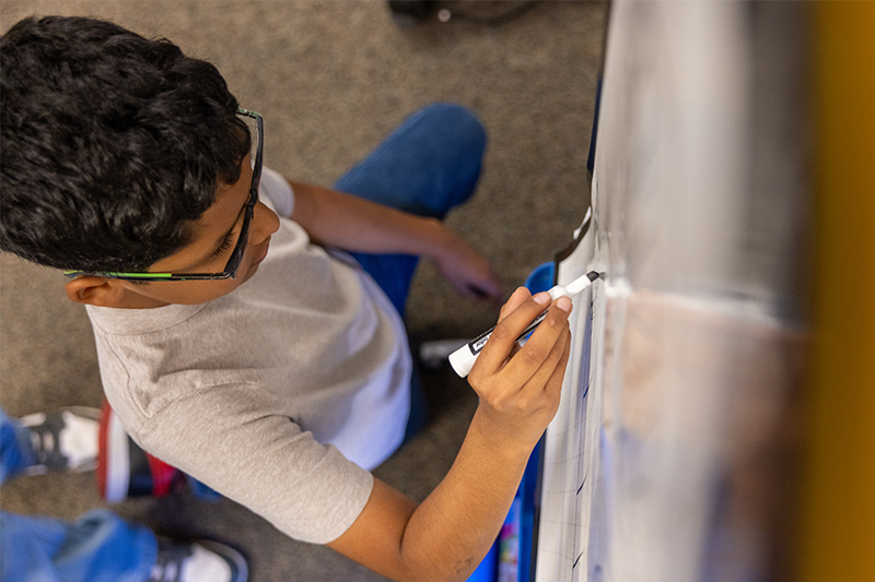 student writing on a whiteboard 