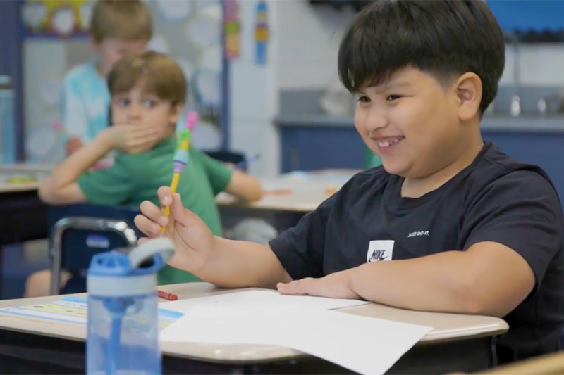 a happy smiling student sitting at a desk